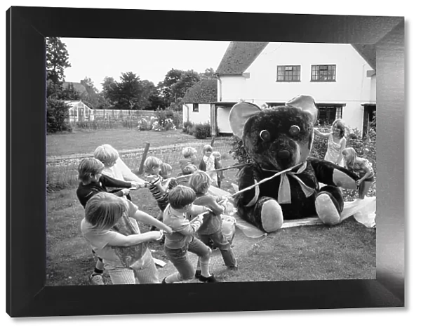 Children from the village of Longarish pull along a giant teddy bear on a trolley through