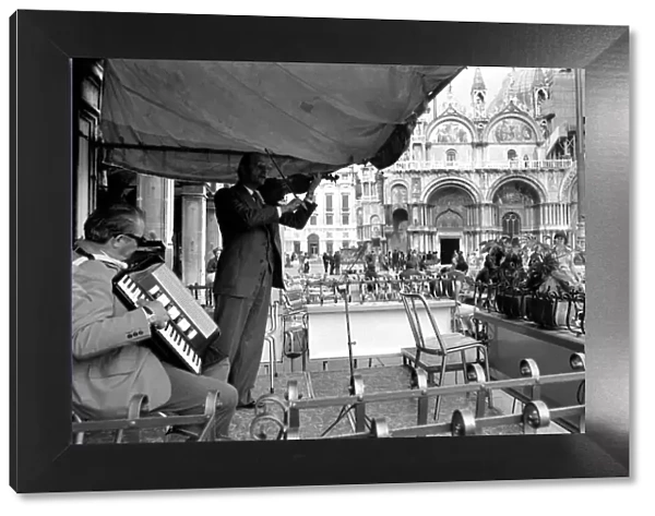 General scenes in Venice. Fiddling while Venice sinks. Signor Ninor Brunello leads a