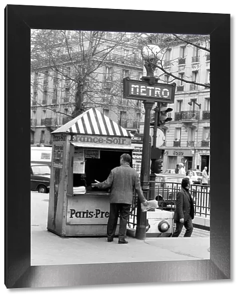 A Morning newspaper reader picks up his paper from a kiosk in the 15th district of Paris
