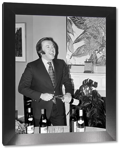 Wine: Mr. David Frost trying to open a bottle of wine at his home