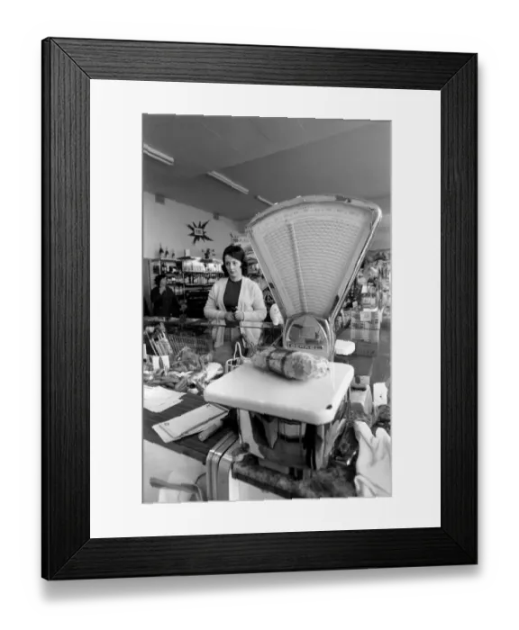 Framed Print : French housewife Mrs Maria Quaranta looks on as her meat is weighed at the local
