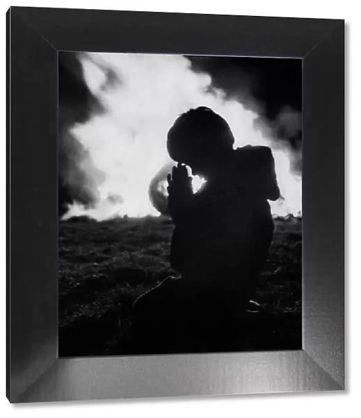 A child prays against the flames of the Bonfire at Stewkley. December 1970 P000327