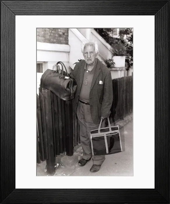 Framed Print : Older gentleman standing holding bags by a fence Framed Print : Older gentleman standing holding bags by a fence