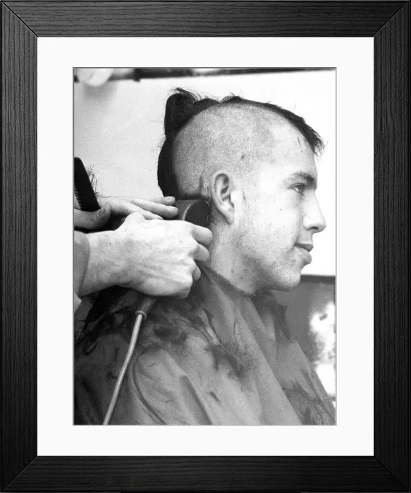 Framed Print : A barber shaves nearly all the hair from this customers head to give him the new look Framed Print : A barber shaves nearly all the hair from this customers head to give him the new look