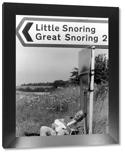 Morris Codling snoozes with his grandson under a signpost in Norfolk