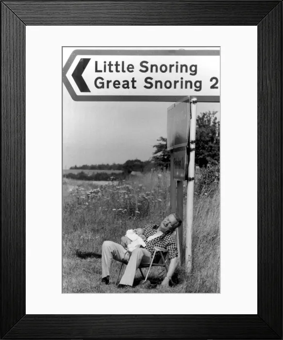 Framed Print : Morris Codling snoozes with his grandson under a signpost in Norfolk