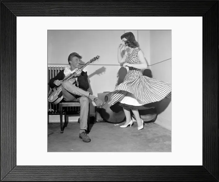 Framed Print : Rock and Roll singer Tommy Steele plays his guitar as girl dances for him, June 1957 Framed Print : Rock and Roll singer Tommy Steele plays his guitar as girl dances for him, June 1957