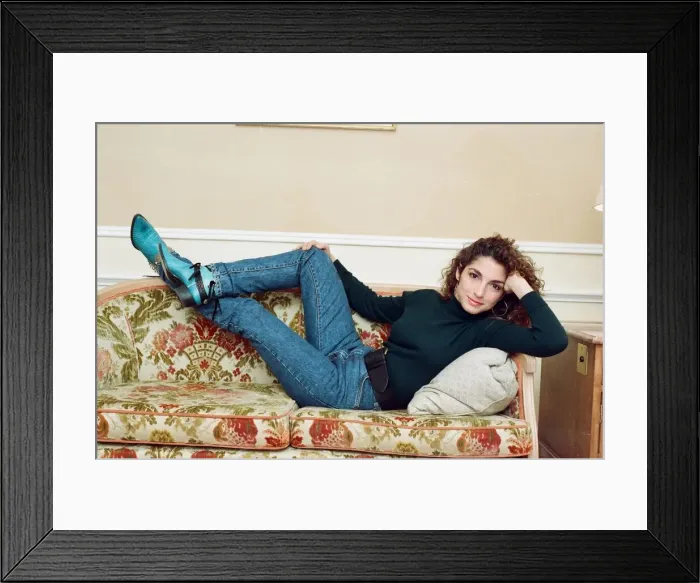 Framed Print : Pop singer Gloria Estefan poses lying down on a sofa in her hotel room on a visit to