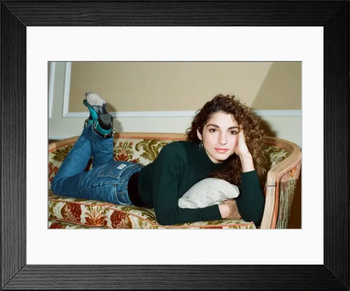 Framed Print : Pop singer Gloria Estefan poses lying down on a sofa in her hotel room on a visit to