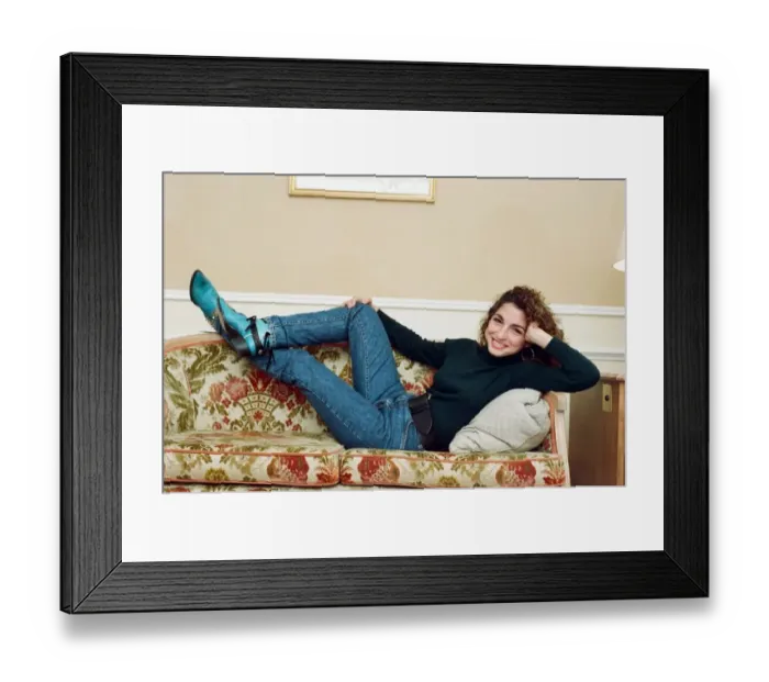 Framed Print : Pop singer Gloria Estefan poses lying down on a sofa in her hotel room on a visit to
