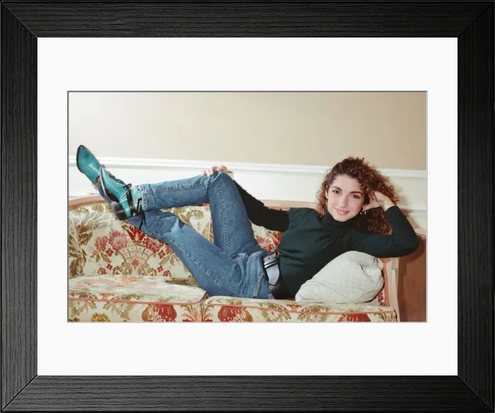 Framed Print : Pop singer Gloria Estefan poses lying down on a sofa in her hotel room on a visit to Framed Print : Pop singer Gloria Estefan poses lying down on a sofa in her hotel room on a visit to