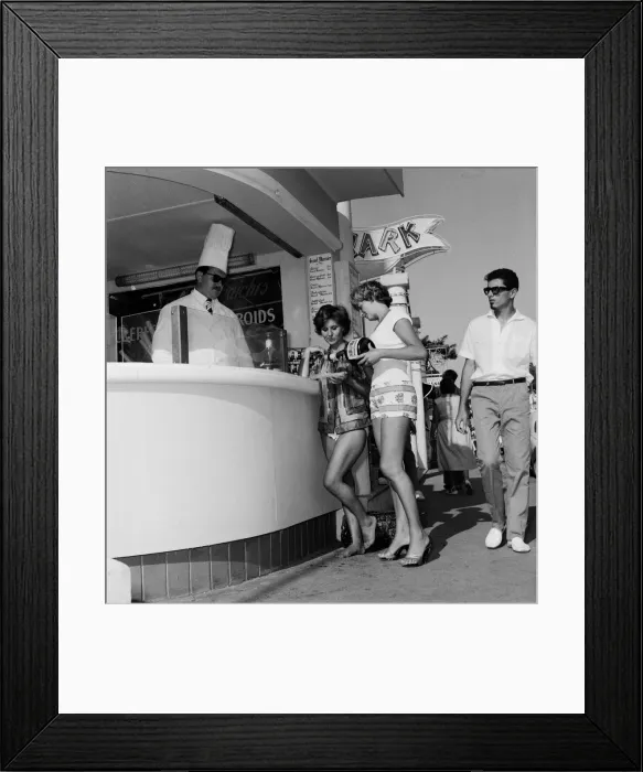 Framed Print : Women queue up to buy a drink from the snack bar on the beach during a holiday Framed Print : Women queue up to buy a drink from the snack bar on the beach during a holiday