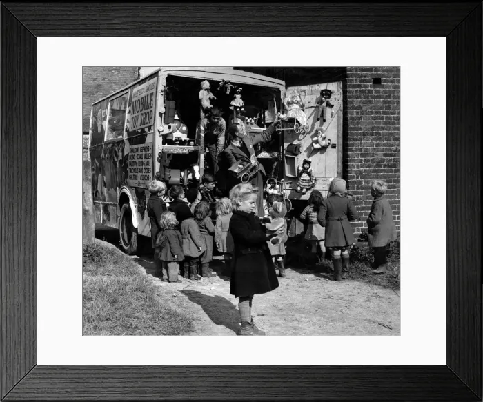 Framed Print : Children looking a the toys on the back of a mobile toy shop
