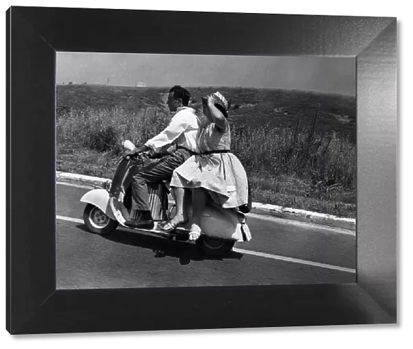 Girl riding sidesaddle on a scooter during a trip in the Italian countryside