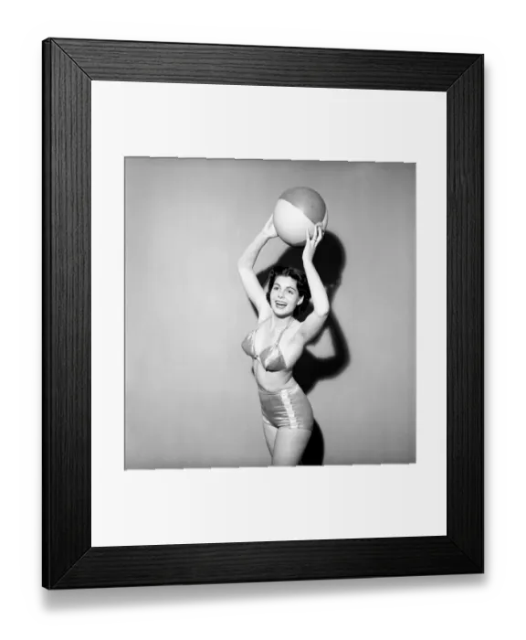 Framed Print : Woman in Swimming costume holding beach ball. 1960 E67-001