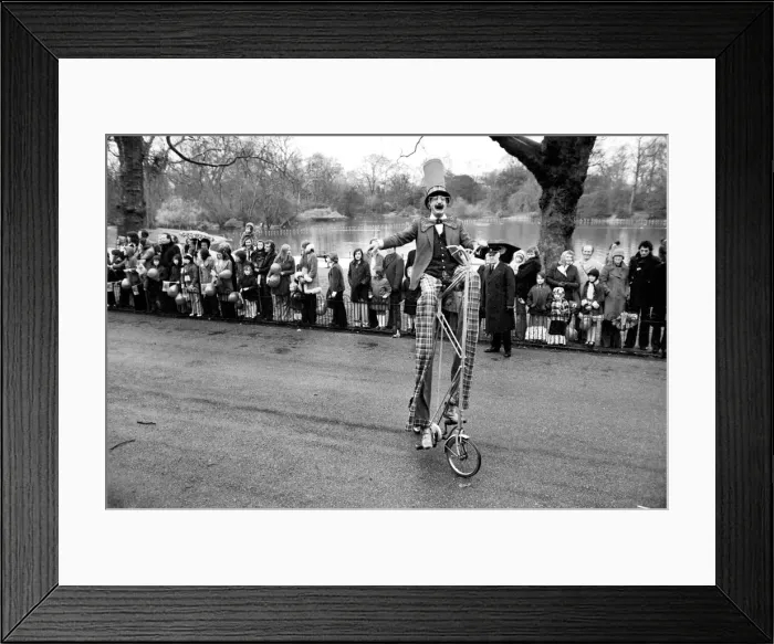 Framed Print : A clown stilt walker seen here riding a oversize bicycle in the Easter parade