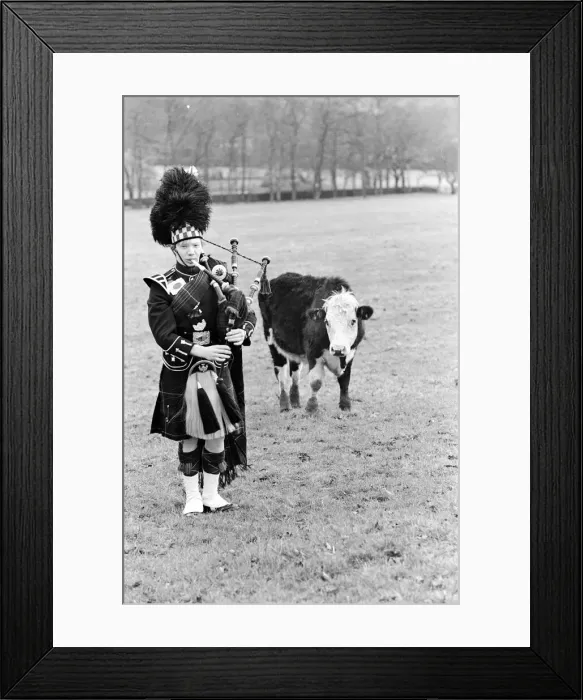 Framed Print : Bagpiper Craig McIntosh practises playing his bagpipes in a field