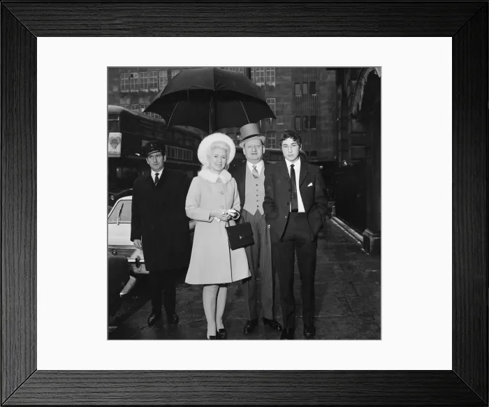 Framed Print : Media Mogul Lew Grade, stands underneath an umbrella with his wife Lady Grade