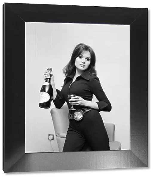 Actress Madeline Smith holding a glass of wine and bottle of champagne at a BBC Press
