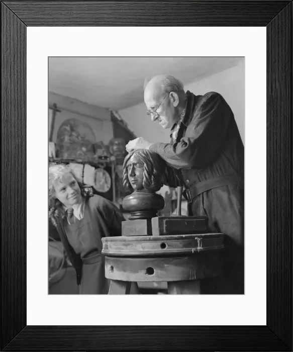 Framed Print : Sculptor William Snell seen here at work in his studio being watch by his schoolgirl Framed Print : Sculptor William Snell seen here at work in his studio being watch by his schoolgirl