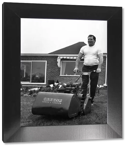 British wrestler Count Bartelli at the helm of a huge lawn mower on the lawn of his home