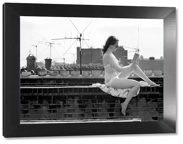 A model wearing a bikini reading a book as she sunbathes on a rooftop on Kings Road in