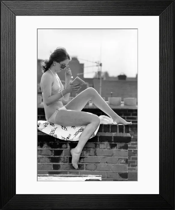 Framed Print : A model wearing a bikini reading a book as she sunbathes on a rooftop on Kings Road in Framed Print : A model wearing a bikini reading a book as she sunbathes on a rooftop on Kings Road in