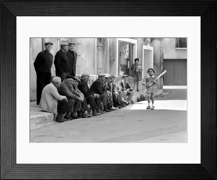 Framed Print : Walking past the old men of Poussan is 6 year old Nathalie Rustan carrying her French Framed Print : Walking past the old men of Poussan is 6 year old Nathalie Rustan carrying her French