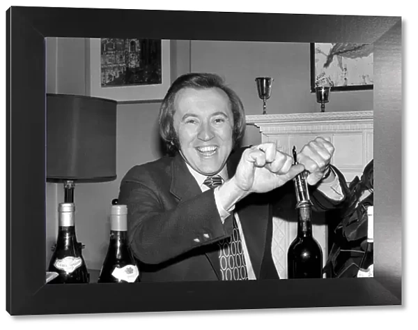 Wine: Mr. David Frost trying to open a bottle of wine at his home. March 1975 75-01338