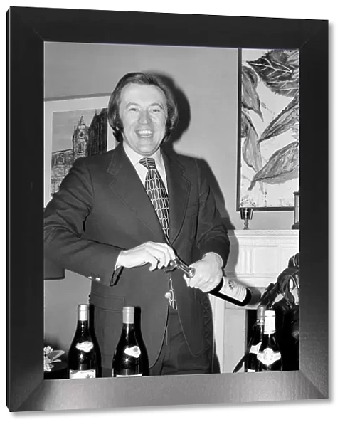 Wine: Mr. David Frost trying to open a bottle of wine at his home
