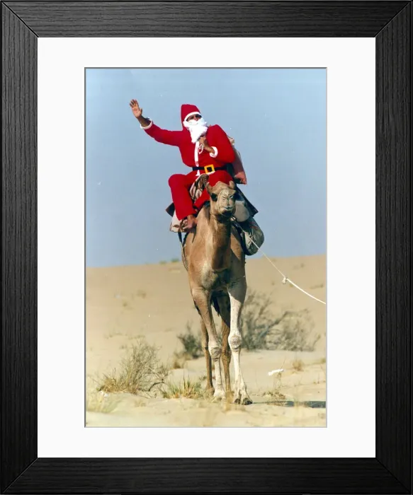 Framed Print : Santa Claus waves from atop his camel in the desert on his way to delivering a message to