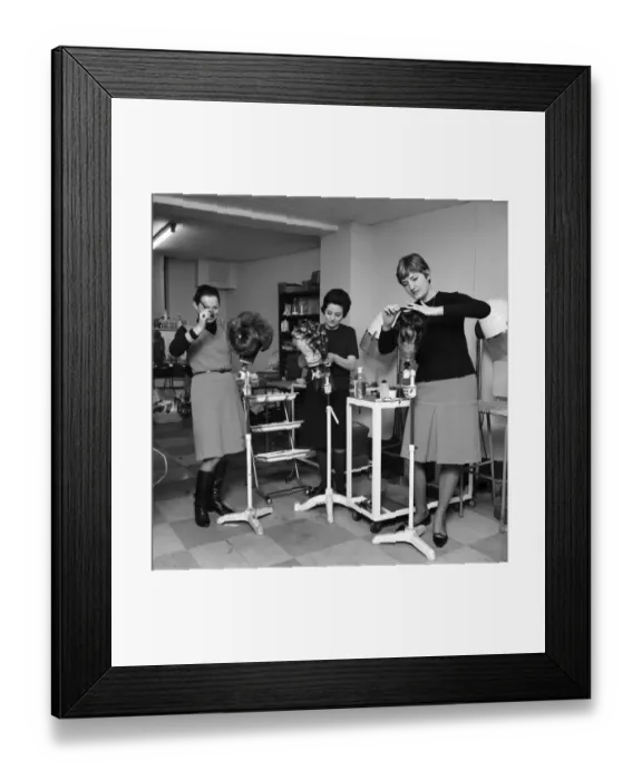 Framed Print : Wigmakers Workshop: Women making wigs whilst in another part of the workshop hair is
