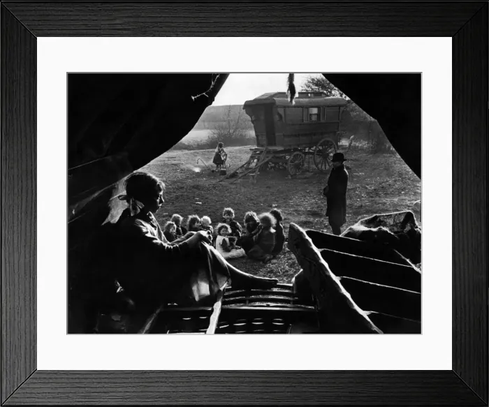 Framed Print : Gipsies in camp. View from inside a tent. A woman sits and thinks while a group of Framed Print : Gipsies in camp. View from inside a tent. A woman sits and thinks while a group of