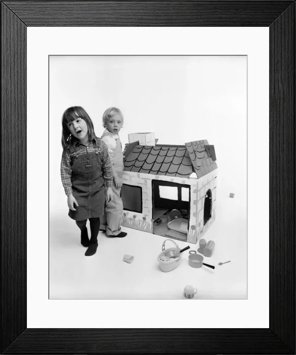 Framed Print : Toys: Children playing with a Wendy house made out of cardboard