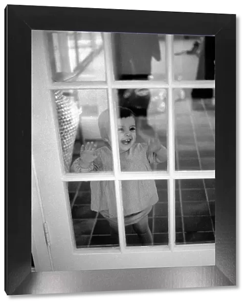 Child of Peter Shelley laughing at him through a glass door, while he plays with his dog