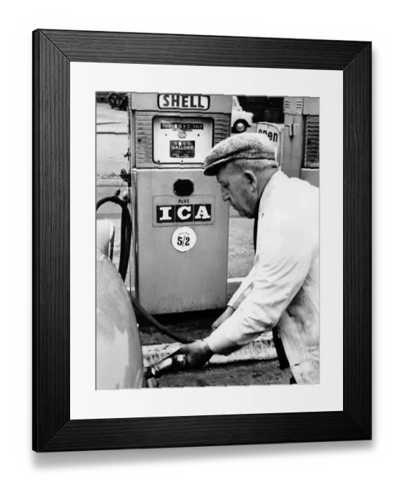 Framed Print : A Petrol pump attendant filling up a cars tank with fuel at a service station