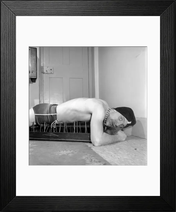 Framed Print : Frank Pepper, Fakir seen here laying on a bed of nails whilst enjoying a cup of tea