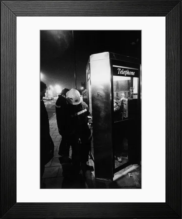 Framed Print : Firefighters free a youngter from a telephhone box jammed shut by his friends
