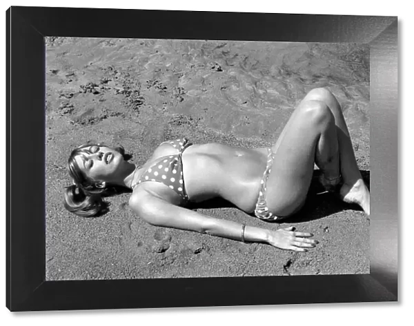 Model wearing a polka dot bikini as she lies on a beach in Africa April 1975