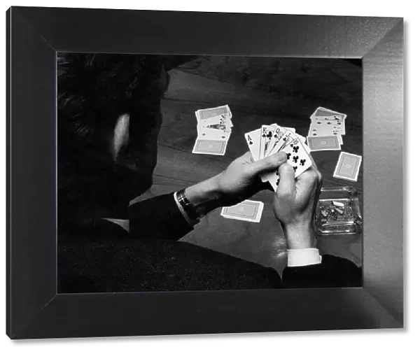 A man holding his hand of cards, a royal flush, while playing poker. February 1972