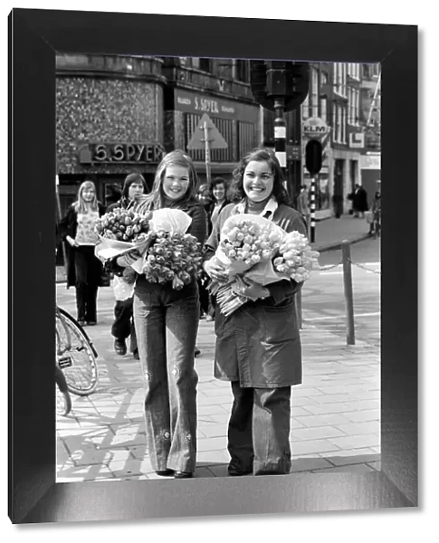 Two young girls of Amsterdam holding bunches of tulips during the season May 1975