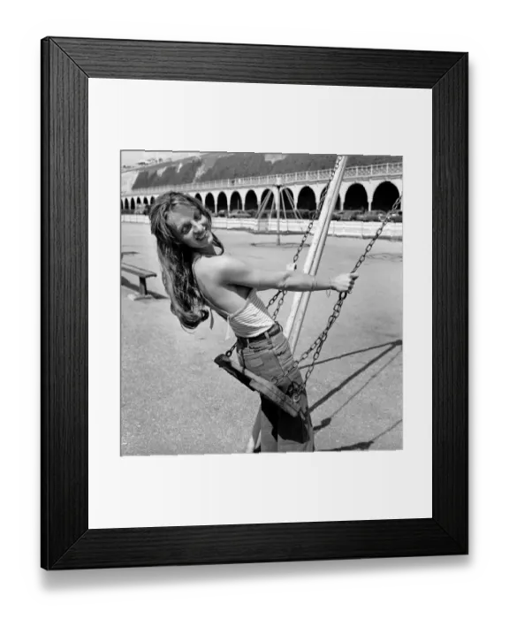 Framed Print : Glamour model wearing a striped vest top and a pair of jeans as she poses on a swing in a Framed Print : Glamour model wearing a striped vest top and a pair of jeans as she poses on a swing in a