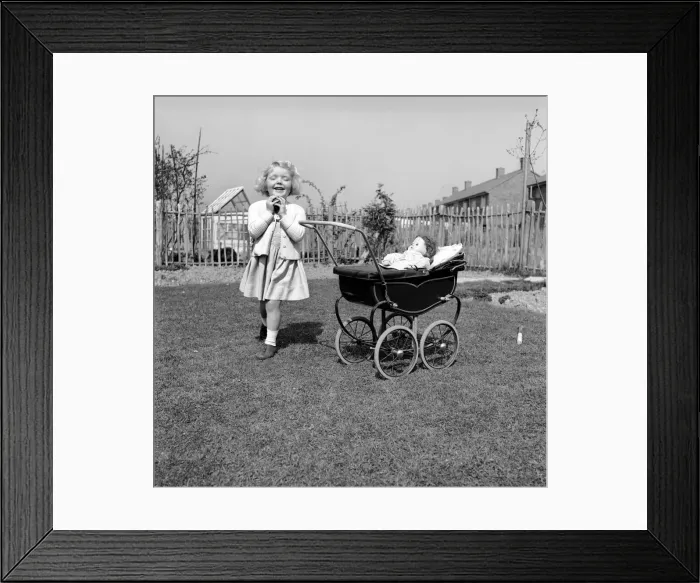 Framed Print : Small girl playing in the garden of her home with a pram and doll. 1954 A228b-002 Framed Print : Small girl playing in the garden of her home with a pram and doll. 1954 A228b-002