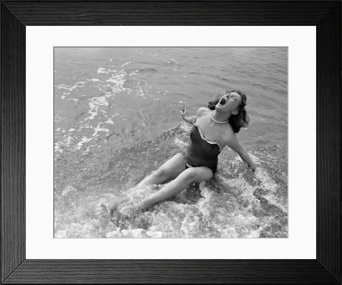 Framed Print : A girl screams out as she sits down in the cold water during a visit to the beach in Framed Print : A girl screams out as she sits down in the cold water during a visit to the beach in