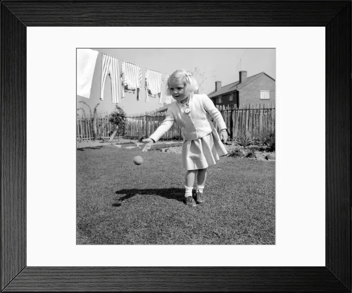 Framed Print : Small girl playing in the garden of her home with a ball. 1954 A228b