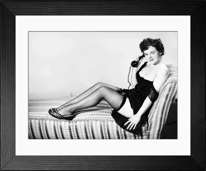 Framed Print : Clothing: Fashion: Stockings and garters. Model sitting in armchair with telephone