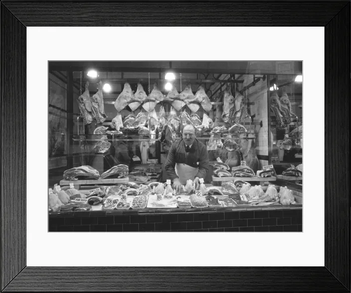 Framed Print : Butcher standing in his shop window, showing off his various meat products currently Framed Print : Butcher standing in his shop window, showing off his various meat products currently