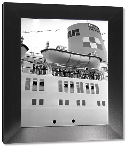 Passengers wave as they stand underneath the lifeboats on the deck of the Empress of