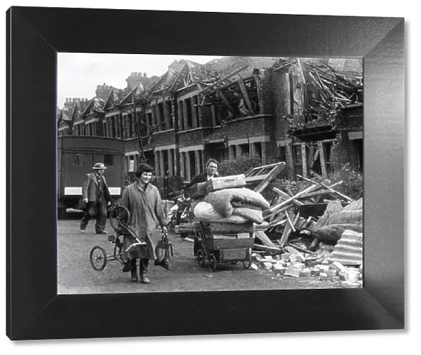 Couple carrying the remaining possessions from their bombed home in a pram following an