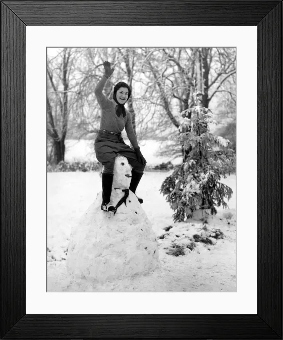 Framed Print : A land army girl in Sussex sitting on top of her Hitler snowman during the Second World Framed Print : A land army girl in Sussex sitting on top of her Hitler snowman during the Second World